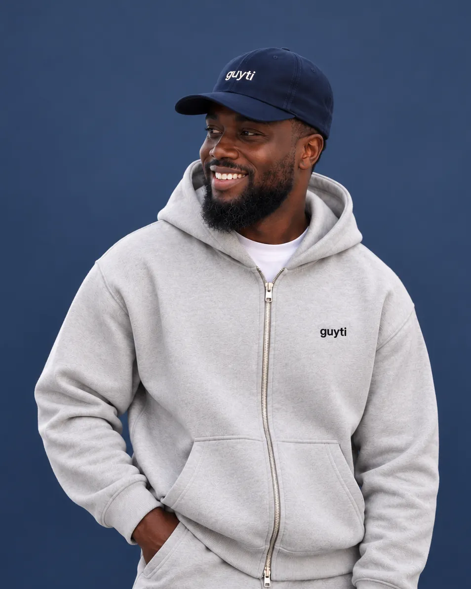 The guyti model in the navy Everyday Signature Cap and an ash Studio Zip Hoodie
